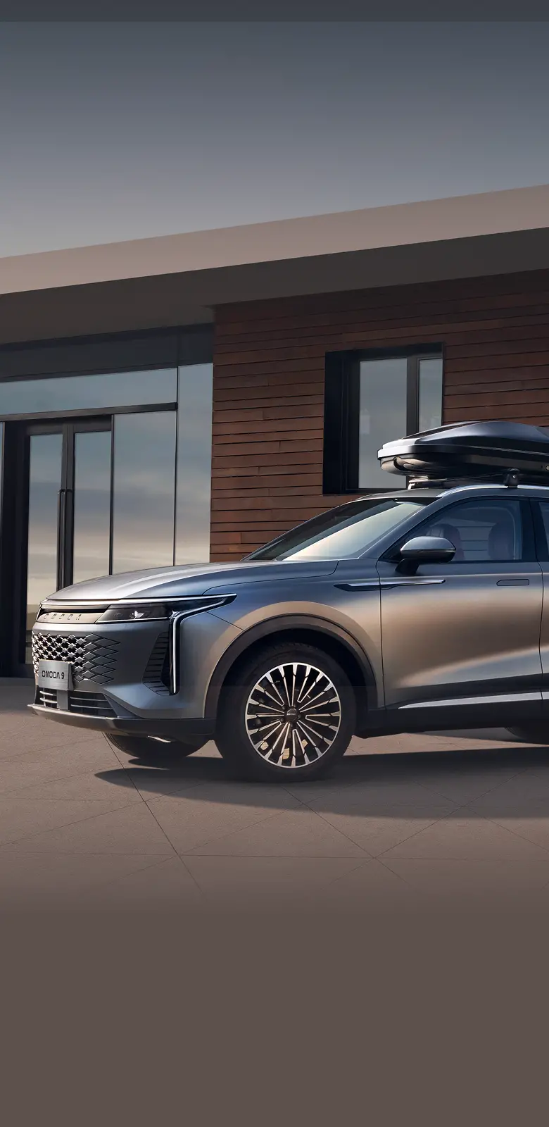 Close up of grey OMODA 9 positioned in front of a wooden building