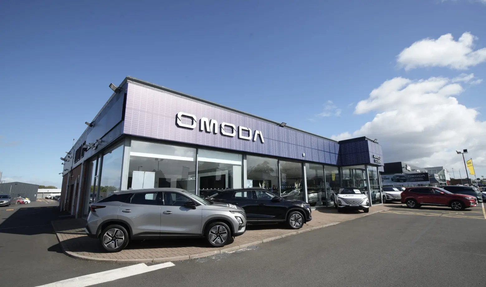 Wide angle shot of OMODA signed building with OMODA cars parked in front
