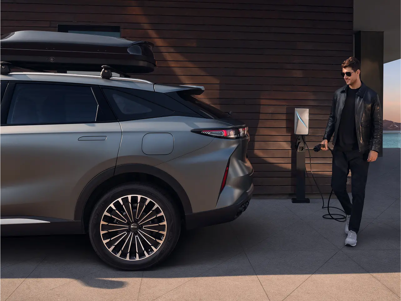 Person walked towards grey OMODA 9 with charging plug in hand