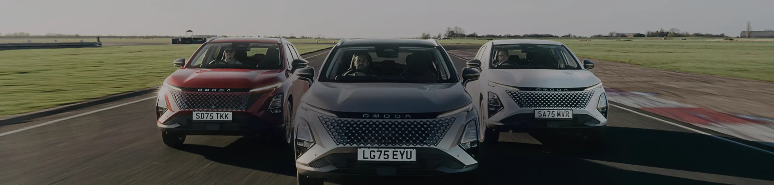Three OMODA 5 SHS-H driving together along the road through a field