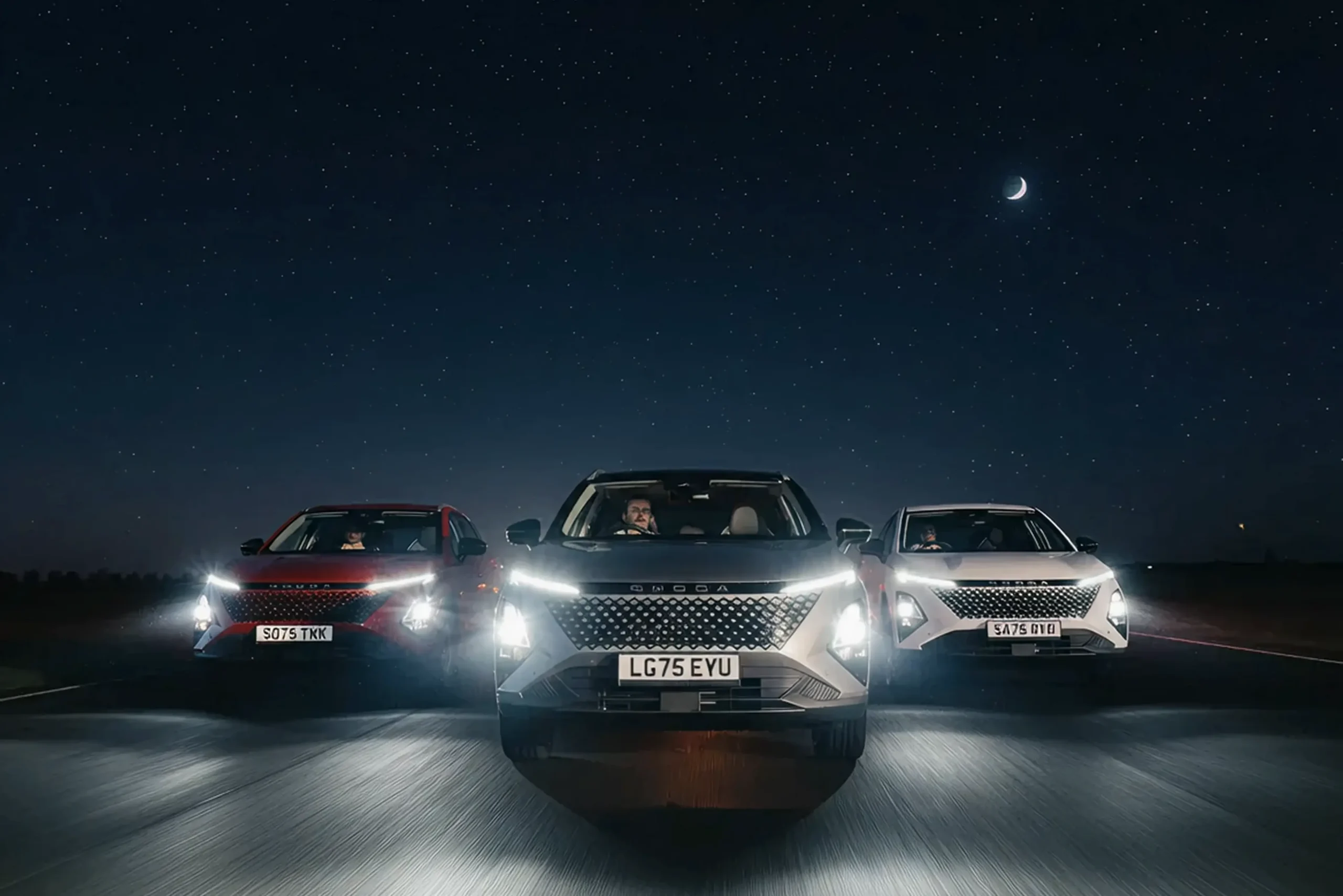 Three OMODA 5 SHS-H SUVs driving together on a road at night